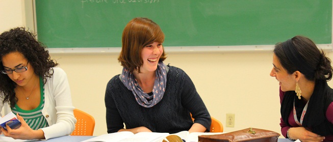 3 women in a classroom, dressed casually and laughing together